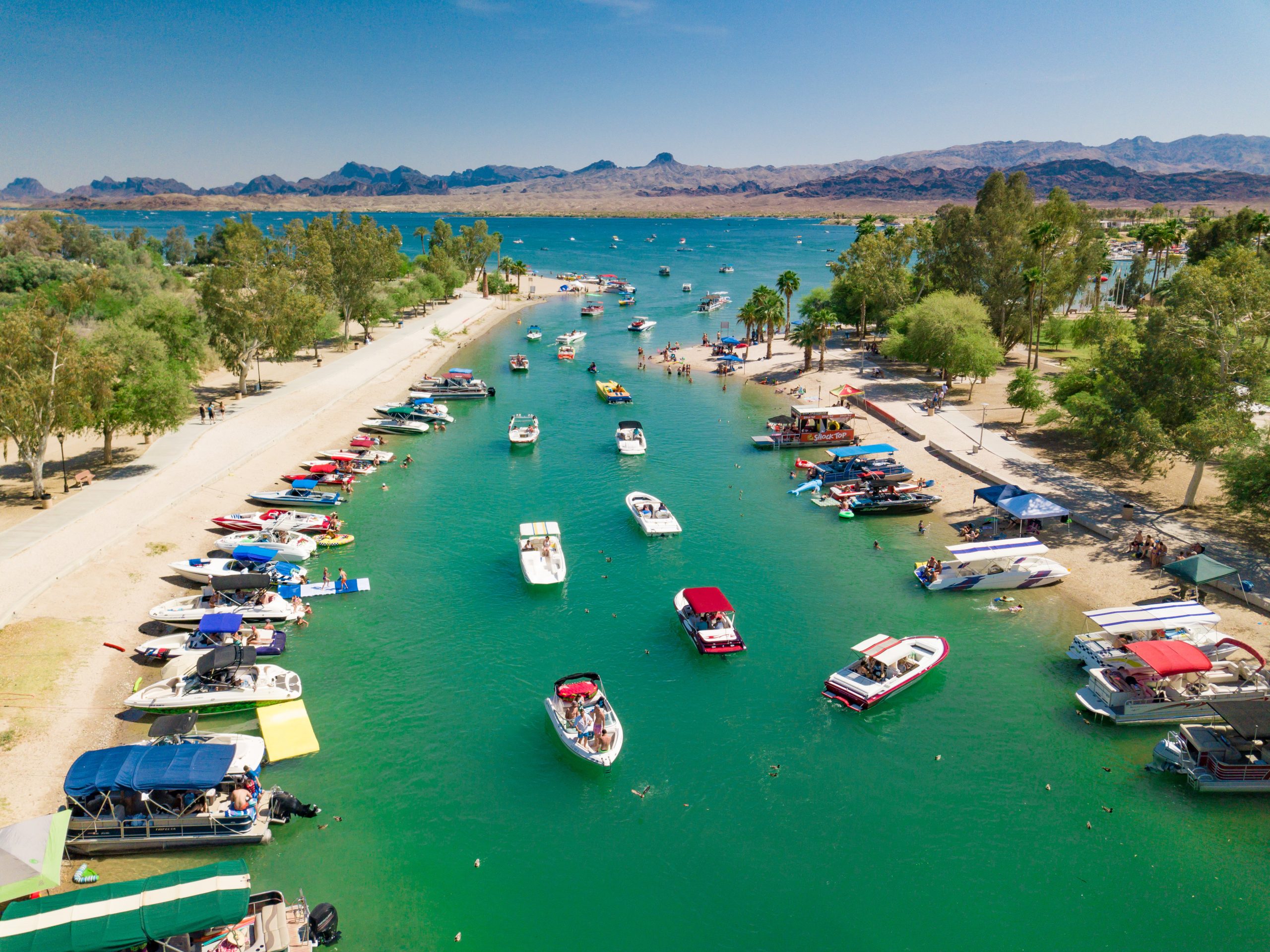 Aerial view of a vibrant marina with boats docked along turquoise waters and sandy shores.